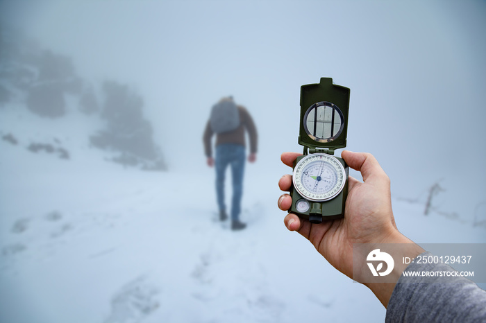 compass in the hand of a traveler against the snow mountains