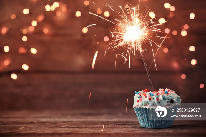 cupcake with sparkler on old wooden background