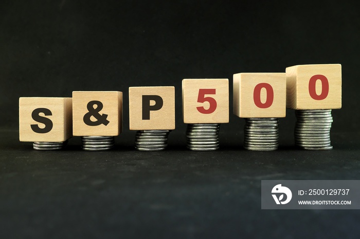 United States US stock market economy growth and recovery concept. S&P500 index in wooden blocks with increasing stack of coins in black background.