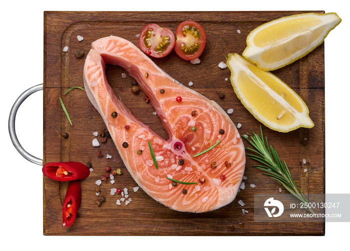 Raw salmon steak on a wooden cutting board, lemon slices, spices. Top view, white isolated background