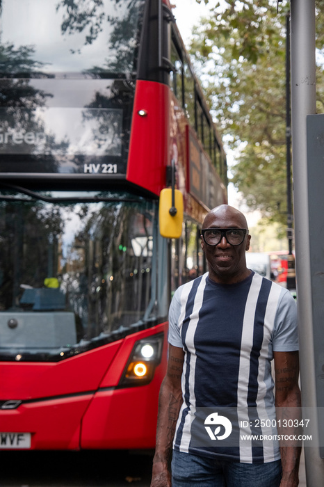 UK, London, Mature man posing next to double decker bus