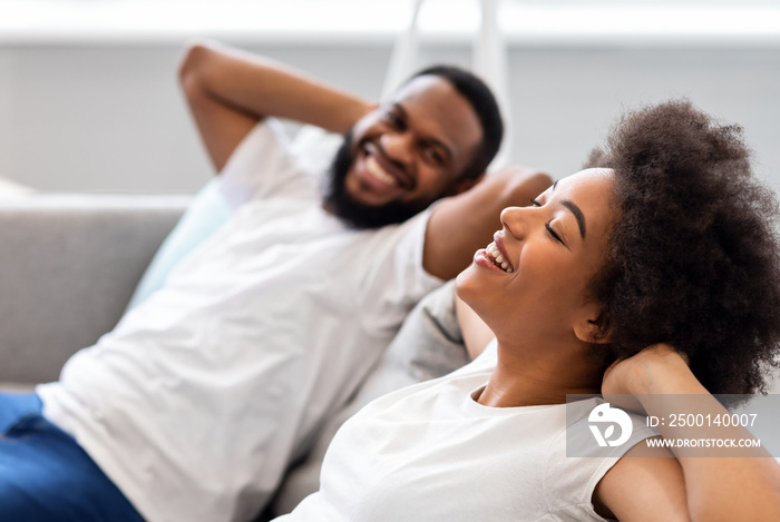 Happy Black Couple Resting Sitting On Sofa At Home