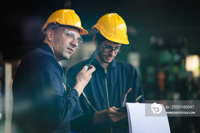 Scene of industrial workers discussing the plan and operation while writing down the note on a clipboard and another worker talking through the walkie talkie, concept manufacturer procedure.