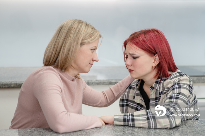 Careful mother and teen daughter sit at home, worried parent calms crying girl. Teenagers problem concept