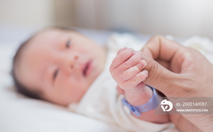 Asian parent hands holding newborn baby fingers, Closeup mother’s hand holding their new born baby. Together love family nursery healthcare and medical father’s day concept