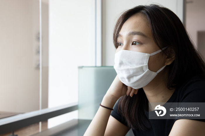 young Asian woman properly wearing face mask in working office, concept of taking precaution measure, social distancing, new normal lifestyle while waiting for coronavirus cure, COVID-19 vaccine.