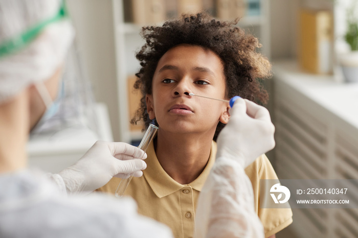 High angle portrait of African-American boy taking covid test during examination in medical clinic, copy space