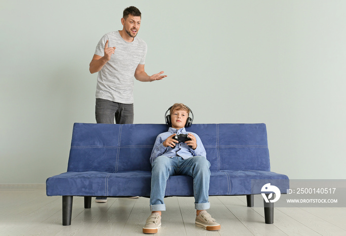 Little boy playing videogame and ignoring his angry father at home