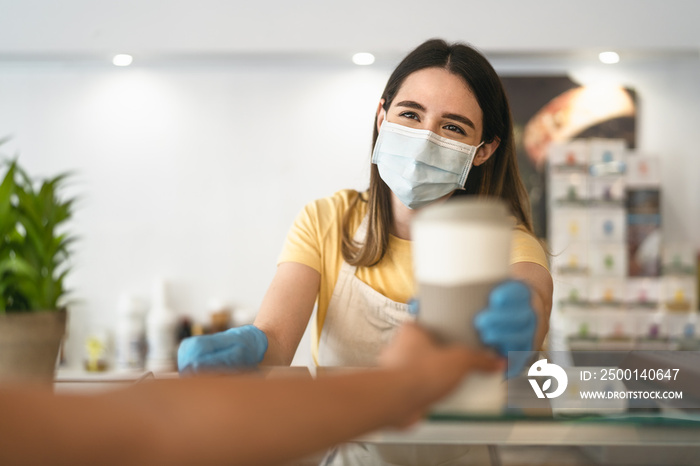 Bar owner working only with take away orders during corona virus outbreak - Young woman worker wearing face surgical mask giving coffee to customer - Healthcare and drinks concept