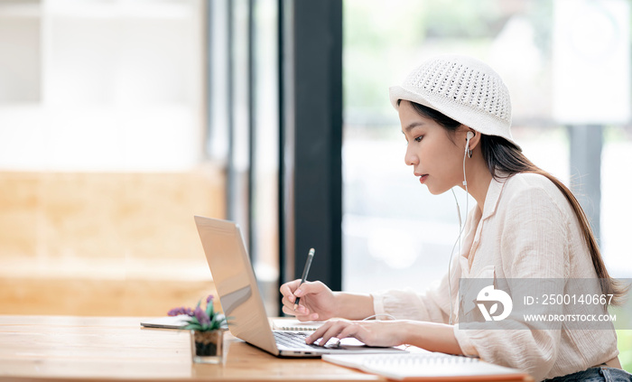 Young university student working on laptop while sitting at the table in library.