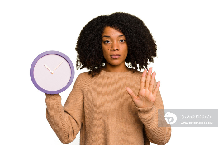 Young African American holding a clock isolated standing with outstretched hand showing stop sign, preventing you.