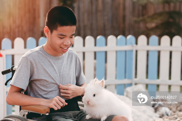 Teenager boy with a disability feeding pets with smile and happy face, Training of muscles through picking, Animals therapy for child with special needs. Rehabilitation and Health Day concept.