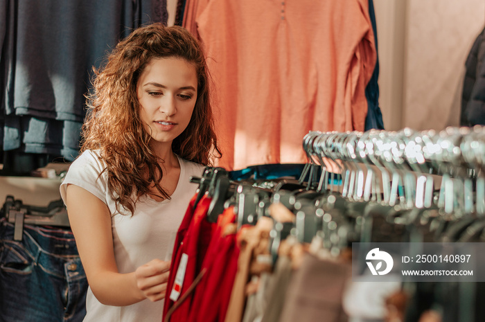 Beautiful girl chooses clothes in shop.