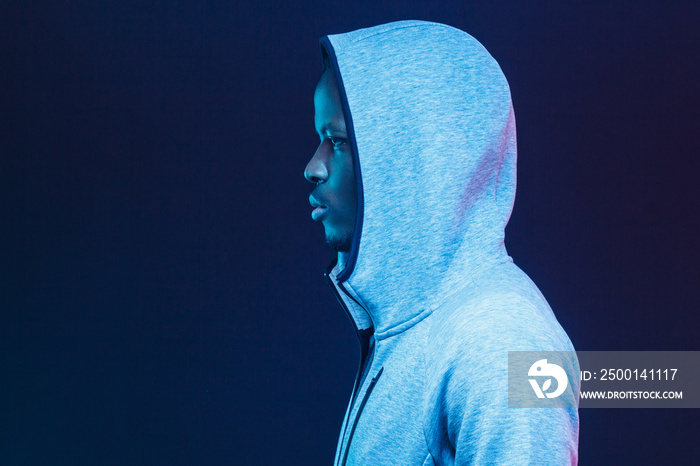 Neon futuristic side portrait of african american young sports man dressed in trendy gray hoodie, looking straight forward