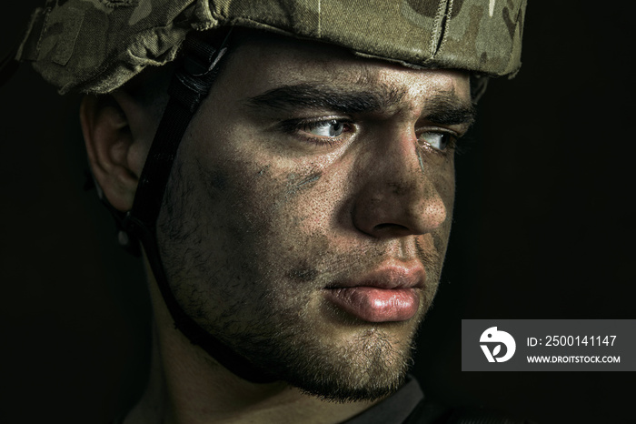 Voices of home and peace. Close up portrait of young male soldier. Man in military uniform on the war. Depressed and having problems with mental health and emotions, PTSD, rehabilitation.
