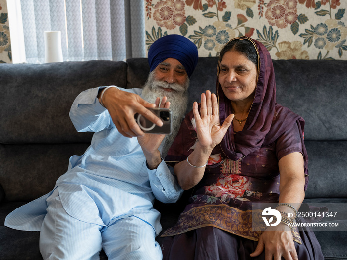 Senior couple in traditional clothing having video call on phone