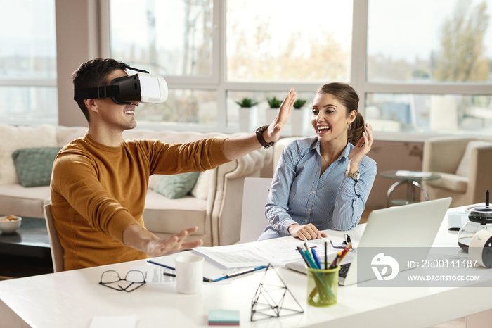 Playful business couple having fun with virtual reality headset.