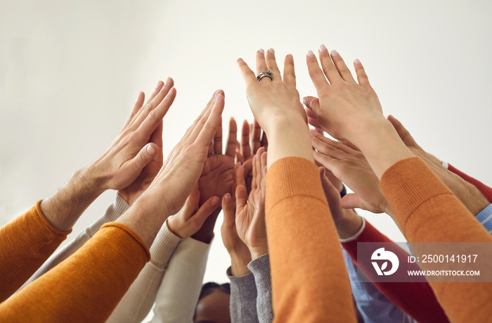 Diverse multiethnic people group holding hands up of raised palms joining together show effective collaboration, success and teamwork force. Business and communication. Closeup shot