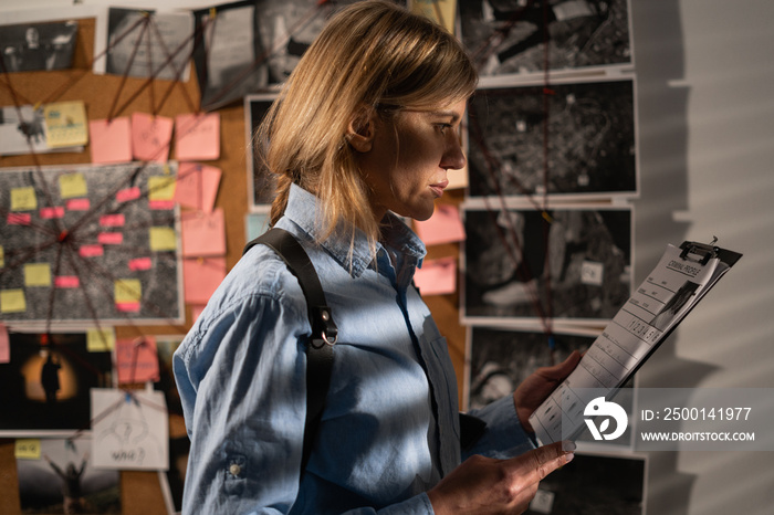 Detective looking at evidence board in her office.