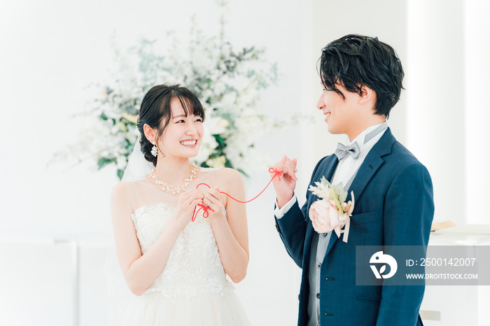 結婚式場で赤い糸で結ばれる新郎新婦（ブライダル・ウェディング）