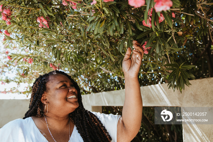 plus size African American woman smelling and looking at pink flowers