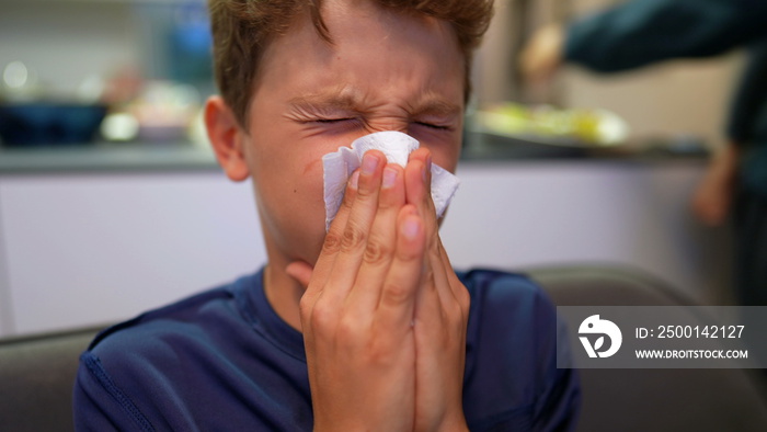 Young boy blowing nose with napkin, child nose blowing