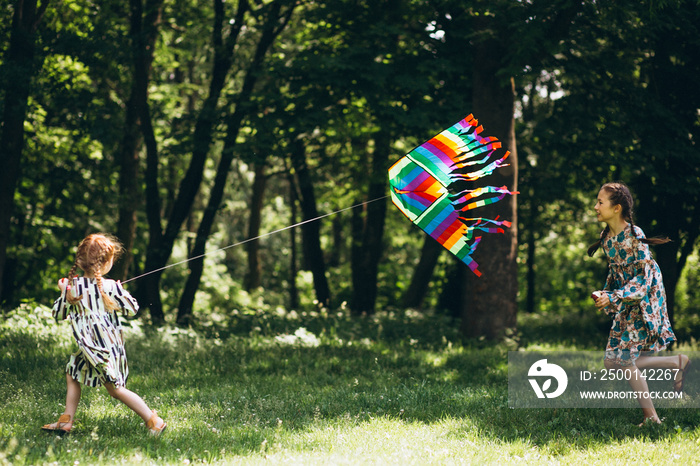 Girls running  in park holding balloons and kite