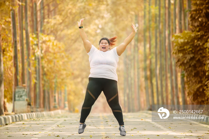 Happy overweight woman jumps at autumn time