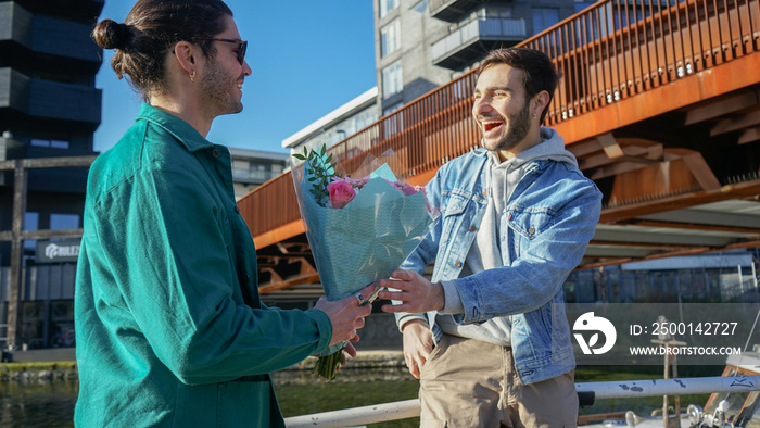 Smiling gay couple with bouquet outdoors