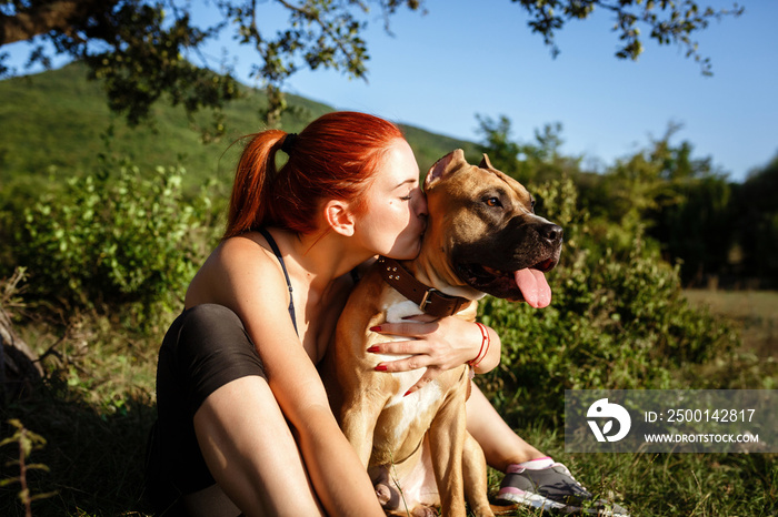 redhair jouful young girl caressing her dog in park