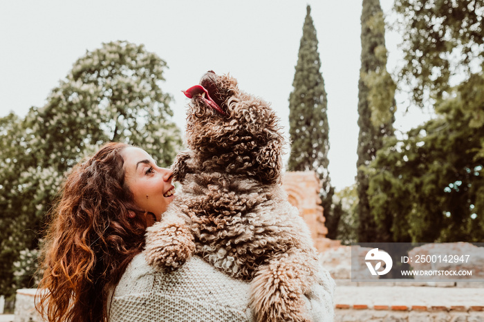 .Young and pretty woman spending free time with her nice brown spanish water dog in a park in the center of the city of Madrid. Lifestyle