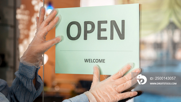 Green Sign Open welcome covid 19 lockdown reopen as new normal. Reopening sign Open on front door entrance. Woman in protective medical gloves hangs Open sign on door. Long web banner