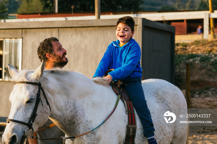 Happy handicapped boy riding a horse during equine therapy