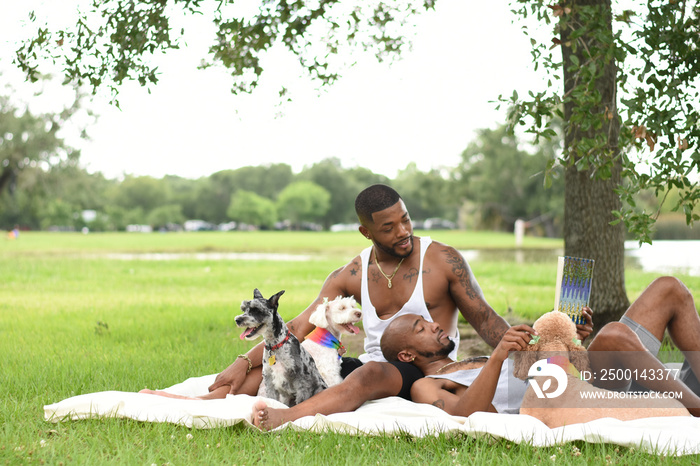 USA, Louisiana, Gay couple with dogs relaxing on lawn in park