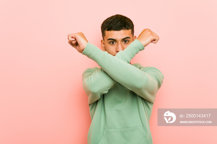 Young hispanic sport man keeping two arms crossed, denial concept.