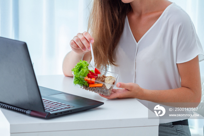 Healthy snack at office workplace. Business woman eating meals from lunch box at working table during lunch break. Food at work