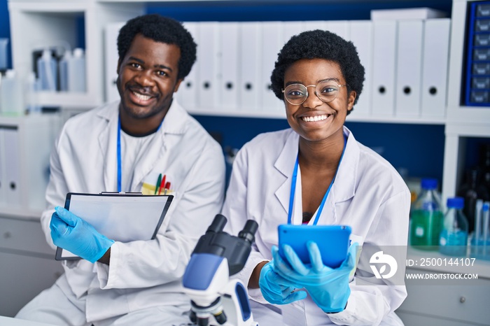 African american man and woman scientists using touchpad write on document at laboratory