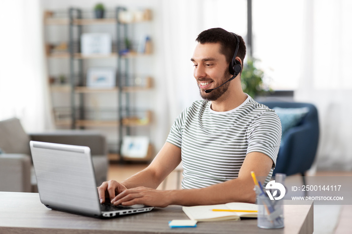 remote job, technology and people concept - happy smiling man with headset and laptop computer having video conference at home office