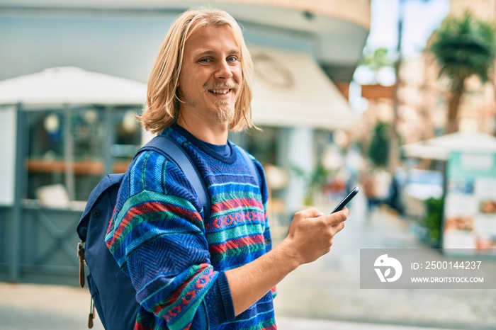 Young scandinavian student man smiling happy using smartphone at the city.