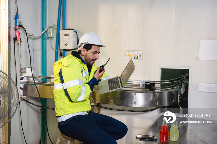 Caucasian engineer man in safety uniform checking and reporting quality a bottled fruit at conveyor belt in processing plant