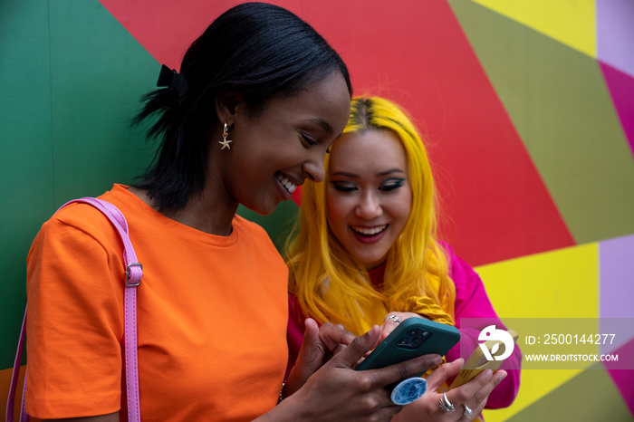 Young female friends using phones outdoors