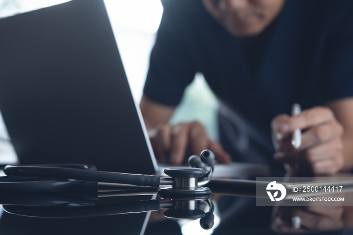 Doctor working on laptop computer and digital tablet in medical office