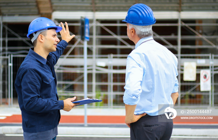 Two architect developers reviewing building plans at construction site