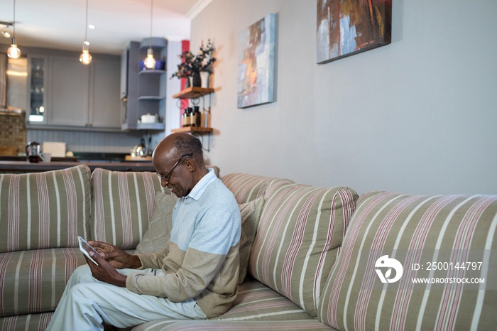 Side view of happy senior man using tablet