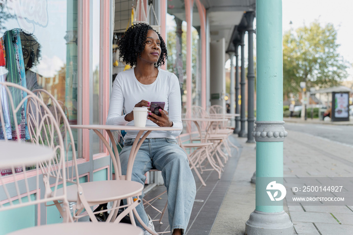 Woman using smart phone during coffee break in sidewalk cafe