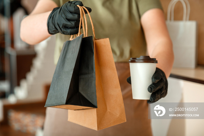 Waiter giving takeout meal while city covid 19 lockdown, coronavirus shutdown. Unrecognizable woman waiter, female hands in gloves work with takeaway orders. Food coffee delivery