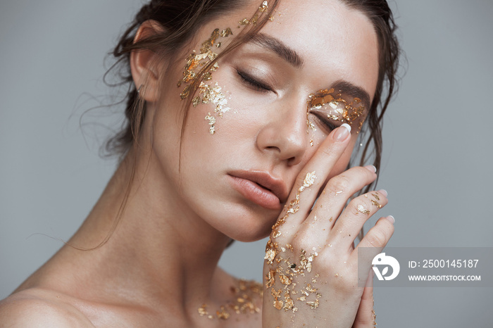 Brunette woman with soft healthy skin and golden makeup