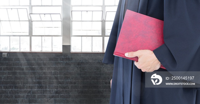 Judge holding book in front of windows and brick wall