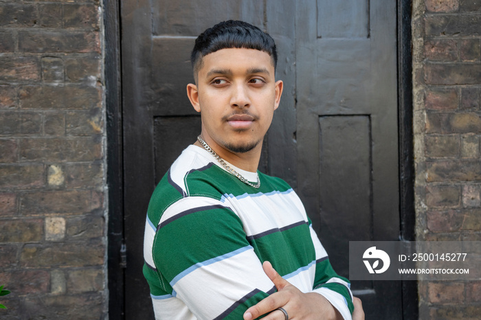 Portrait of young man wearing striped sweatshirt and looking away