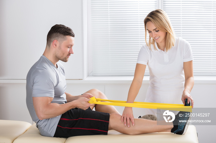 Female Physiotherapist Giving Exercise With Band